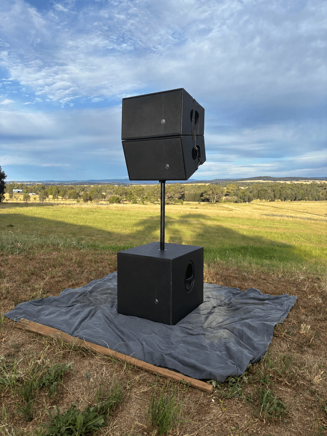 Pair of Mackie HDA tops stacked on a subwoofer pole in a paddock